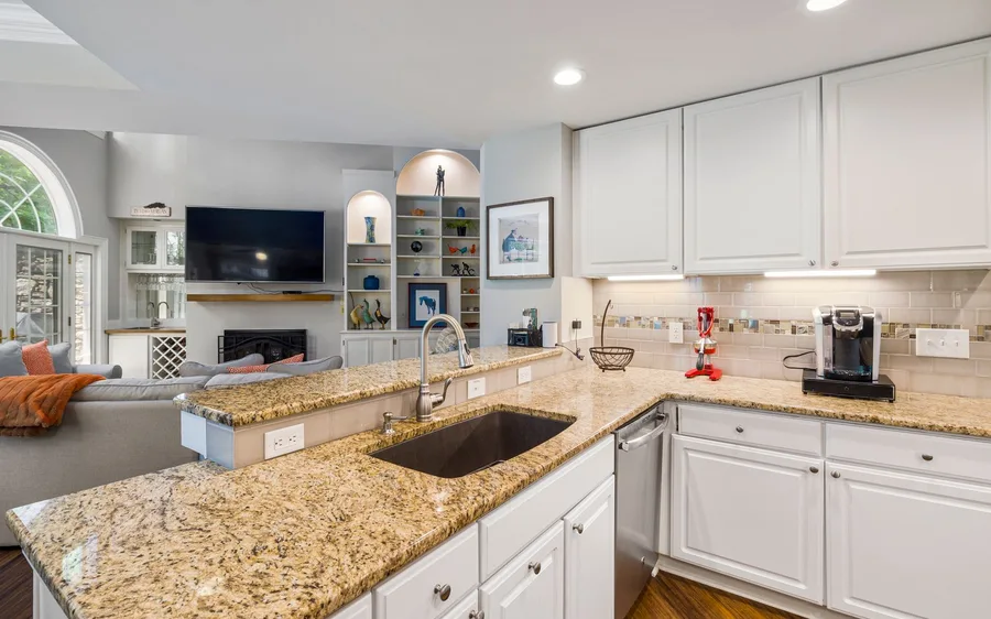 A gloved hand wiping down a clean stone countertop